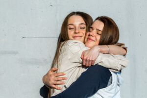 Relationships concept showing two teenage girls hugging each other